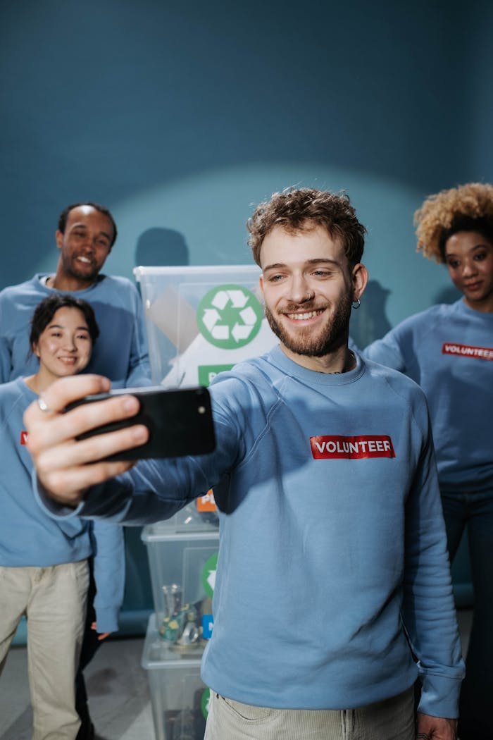 A diverse group of volunteers in blue shirts taking a selfie during a community service event.